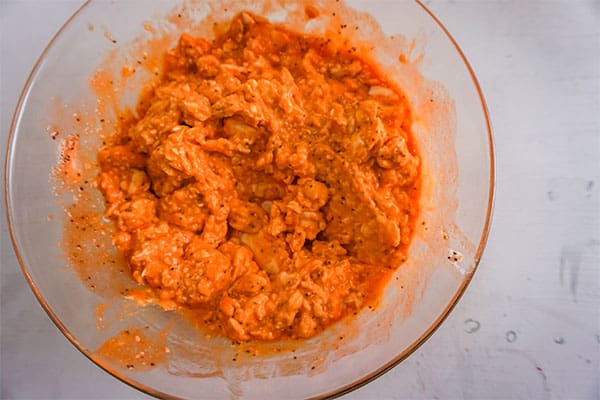 baked buffalo chicken dip  in a glass bowl on a white background