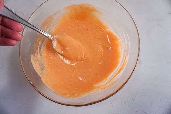 a spoon in a glass bowl of hot sauce