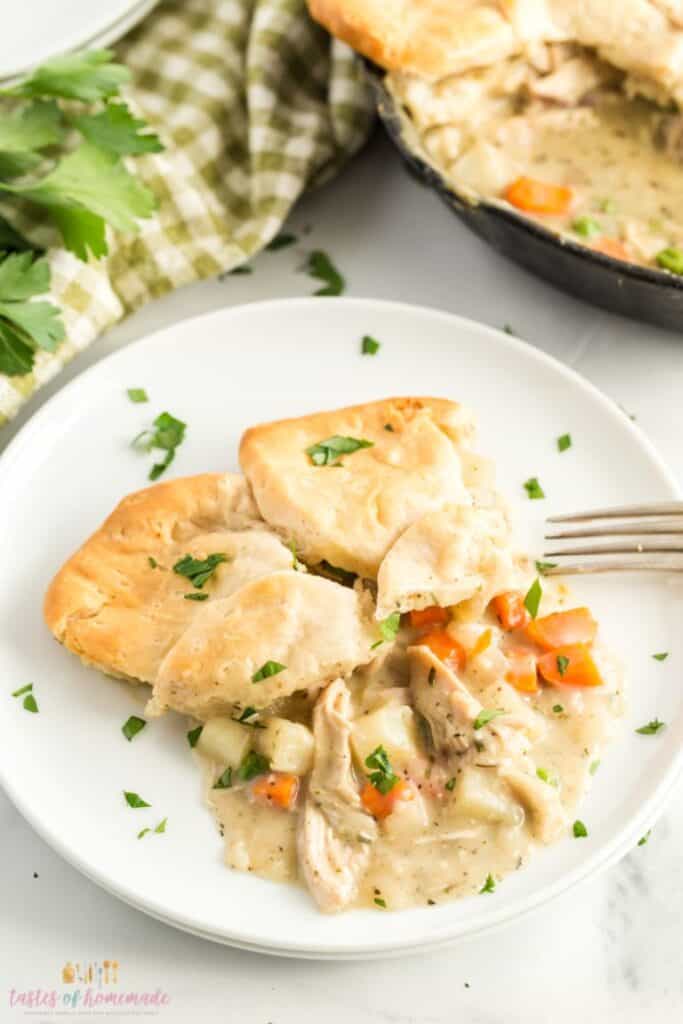 chicken pot pie on a white plate next to a fork on a white counter