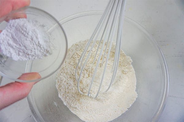 dry ingredients being combined with a whisk in a glass bowl