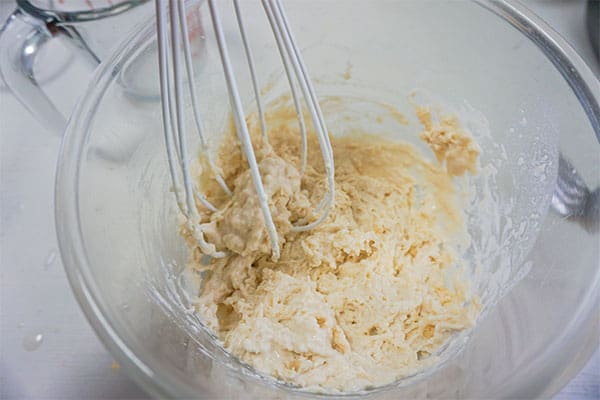 ingredients for biscuits being whisked together in a glass bowl on a white background
