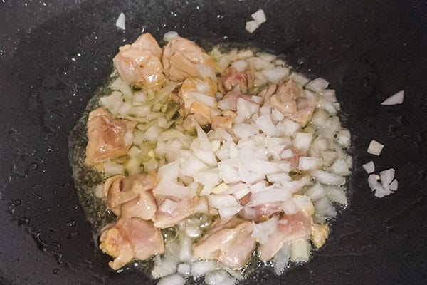 oil, chicken, onion and garlic cooking in a skillet