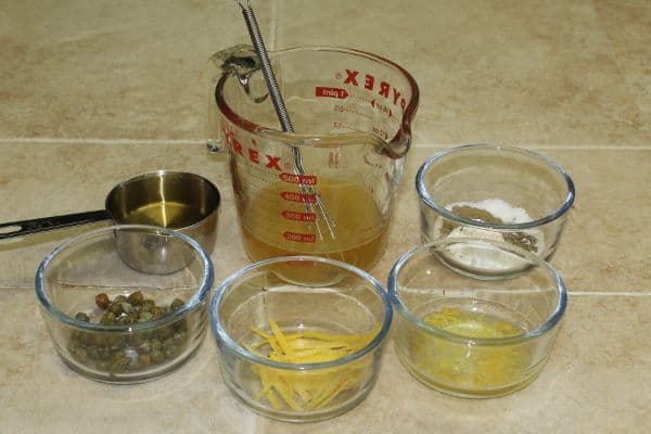 glass and metal containers of olive oil, chicken broth, seasonings, butter, lemon zest and capers