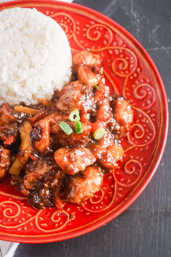 Slow Cooker General Tso's Chicken next to some rice on a red plate