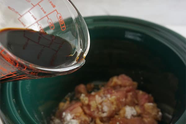 adding soy sauce to chicken mixture in the slow cooker