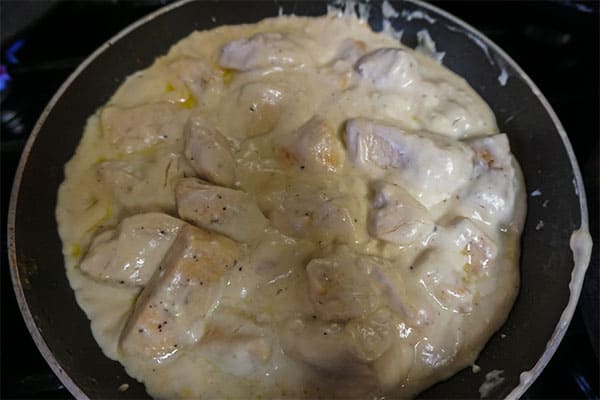 chicken, garlic, seasoning, whipping cream and cheese cooking in a skillet