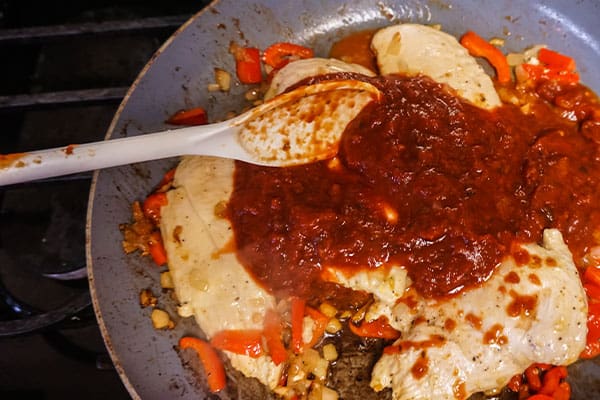 chicken and sauce and a spoon in a skillet