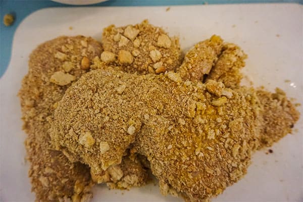 chicken breasts covered in breadcrumbs on a white plate