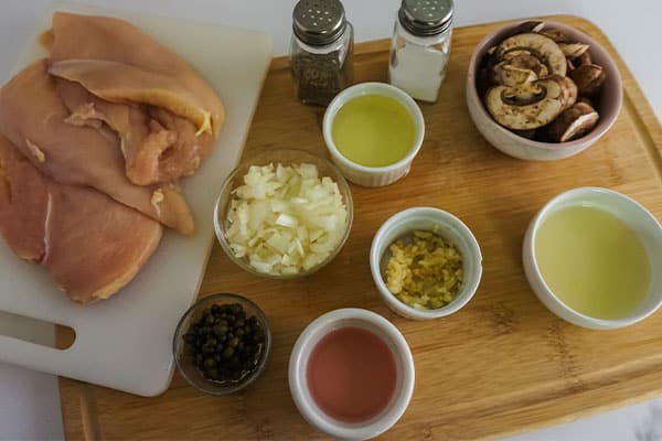 ingredients on cutting boards and bowls needed to make Homemade Chicken Piccata