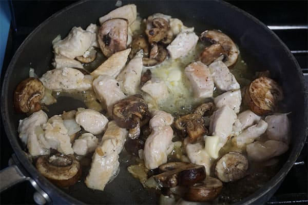 mushrooms, diced chicken and onions cooking in a skillet