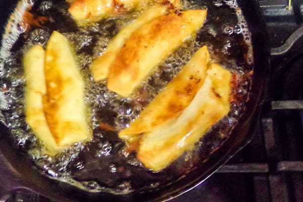chicken chimichangas frying in oil in a skillet