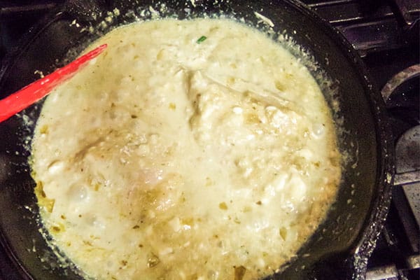 a red spoon stirring Chicken Chile Verde in a skillet