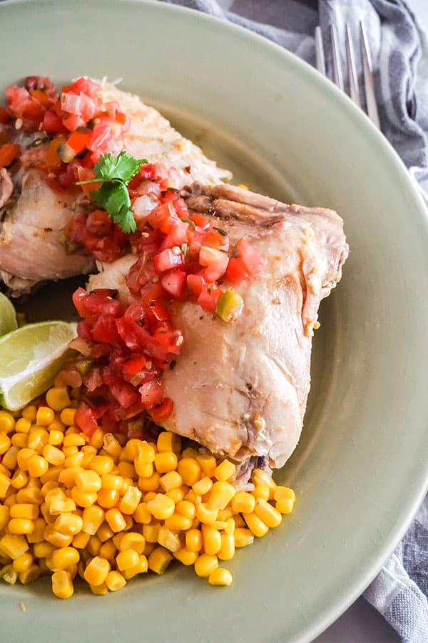 a closeup of  Cilantro Lime Chicken next to corn on a green plate 