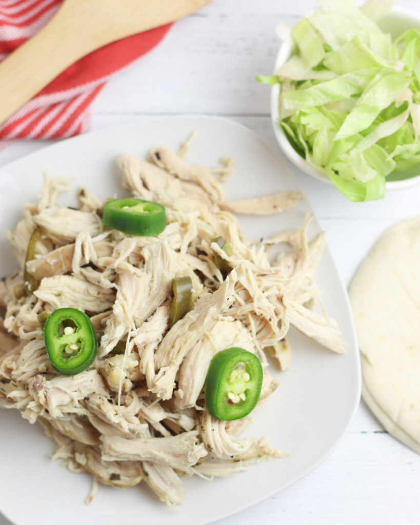 crock pot Shredded Chicken on a plate next to lettuce and tortillas.