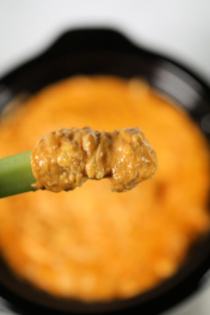 a closeup of the best crock pot chicken buffalo dip on a celery stalk.
