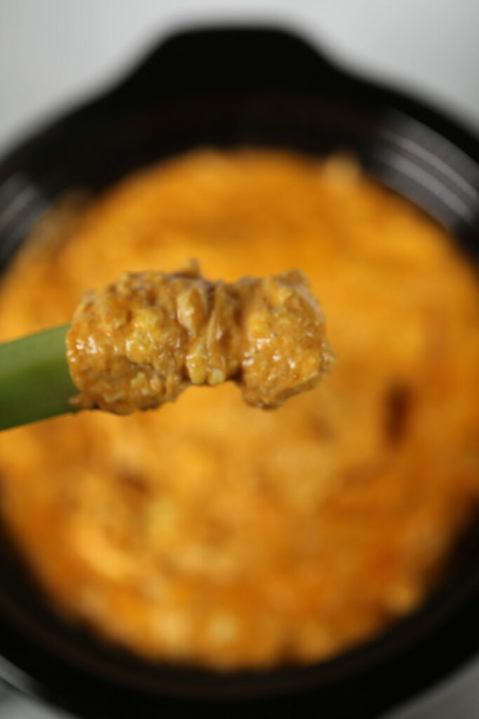 a closeup of the best crock pot chicken buffalo dip on a celery stalk.