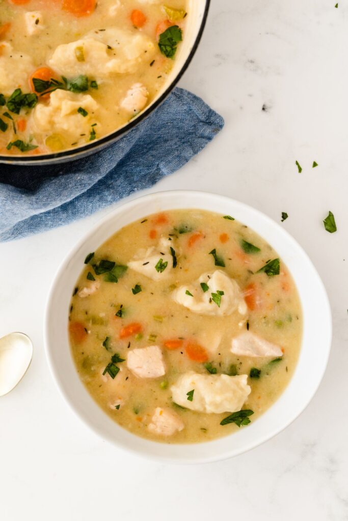 Creamy Chicken and Dumpling Soup in a bowl garnished with chopped parsley. 