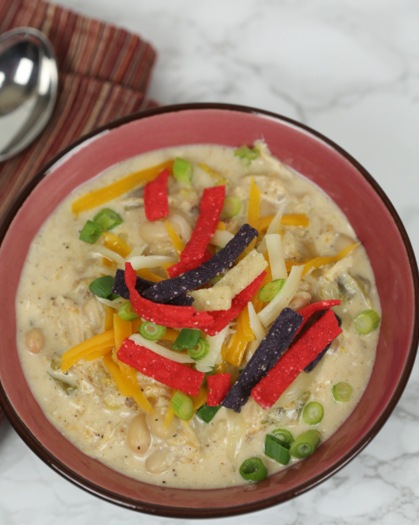 easy Crock Pot white Chicken Chili in a bowl topped with tortilla stirps and green onions. 