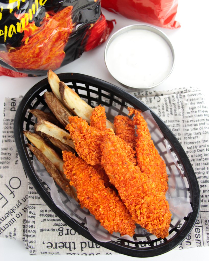 doritos chicken strips and fries in a basket next to dipping sauce.