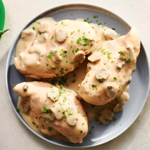 three chicken breasts smothered in gravy and mushrooms