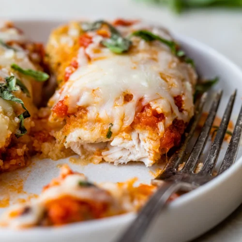 piece of chicken topped with tomato sauce and cheese