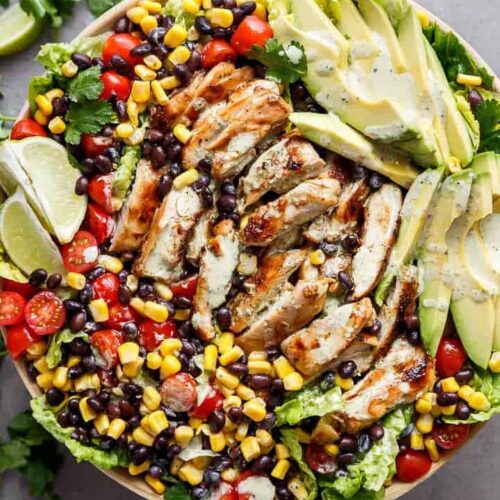 salad topped with chicken, vegetables, beans, and dressing