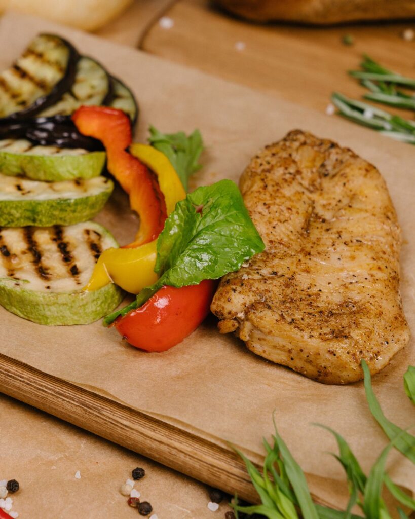 a chicken breast next to grilled vegetabels.