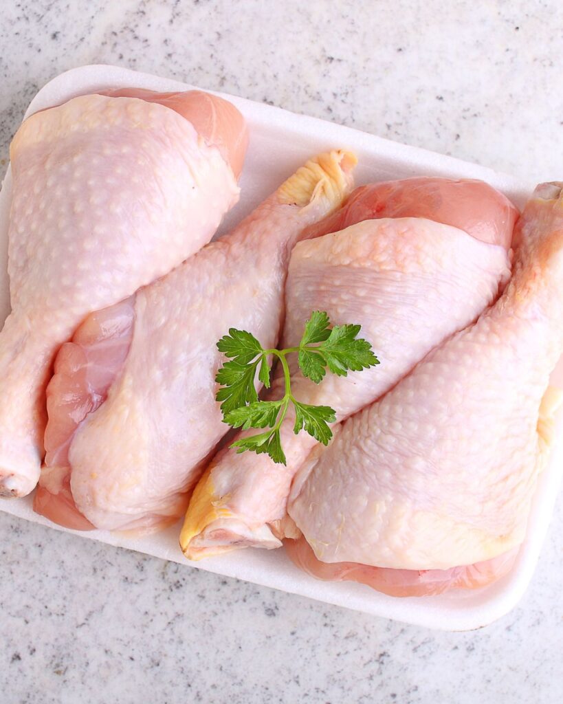 uncooked chicken legs  in a white tray.